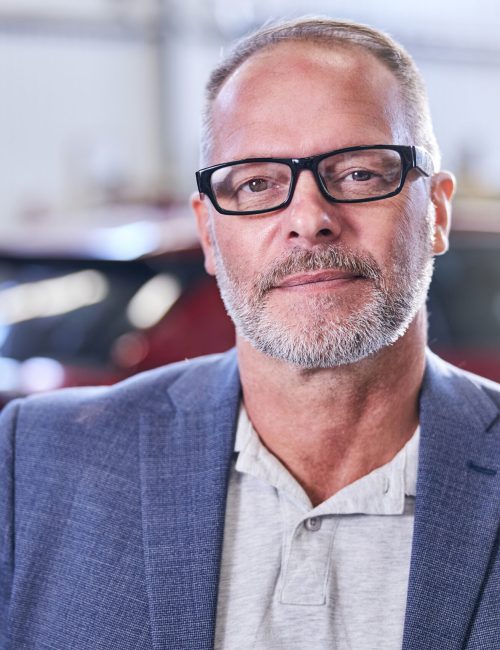 Handsome gentleman wearing glasses and gray jacket while looking at camera and smiling